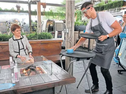  ?? PA. ?? First Minister Nicola Sturgeon is served a coffee by Jamie Buchta during a visit to Cold Town House in Edinburgh’s Grassmarke­t ahead of the reopening of outdoor cafés and beer gardens today.