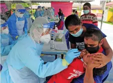  ?? — Bernama photo ?? Medical assistant taking sample for Covid-19 screening from a toddler at Orang Ramai Meru 3 community hall, Klang yesterday.