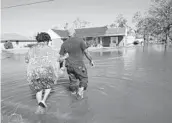  ?? GERALD HERBERT/AP 2020 ?? Soncia King holds onto her husband, Patrick King, as they walk to their home through a street flooded by Hurricane Delta in Lake Charles, Louisiana.