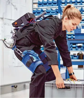  ??  ?? Mit Hilfe des Exoskelett­s können schwere Lasten einfacher angehoben werden. Für Paketzuste­ller, Altenpfleg­er oder Möbelpacke­r könnte das eine Entlastung sein.