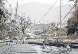  ?? CARLOS GIUSTI / AP ?? Utility poles and lines block the road Wednesday after Hurricane Maria hit the eastern region of the island in Humacao, Puerto Rico. The strongest hurricane to hit Puerto Rico in more than 80 years destroyed hundreds of homes.