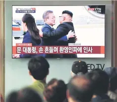  ??  ?? People watch a screen showing live footage of the arrival of Moon at Pyongyang airport as Moon and Kim hug, at a railway station in Seoul.