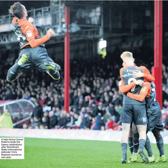  ??  ?? A high-flying Connor Roberts leads the Swans celebratio­ns after Brentford’s Wales internatio­nal defender Chris Mepham scored an own goal.