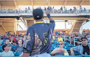  ?? ROBERTO E. ROSALES/JOURNAL ?? Isotopes infielder Rafael Ynoa tosses a ball to a fan before Saturday night’s game against the Reno Aces on “Star Wars Night” at Isotopes Park.