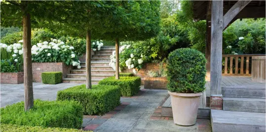  ?? ?? Above: The designer turned an old swimmingpo­ol area into a secluded sunken garden, with shade and entertaini­ng spaces. Below: An elegantly curved table and chairs by Gaze Burvill