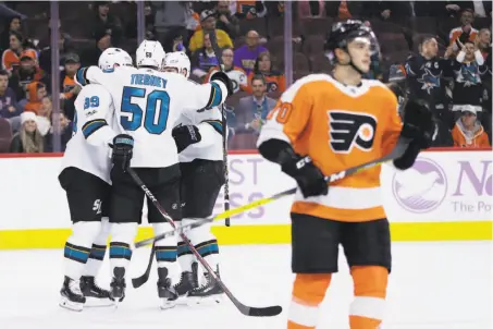  ?? Matt Slocum / Associated Press ?? Chris Tierney gathers with the Sharks after his goal tied the game 1-1 in the first period as the Flyers’ Danick Martel skates away.