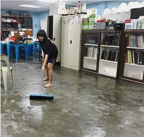  ??  ?? Helping hands: A student cleaning a music room while Wee (right) lends a hand to hose off muddy water in the basketball court after the flood at SMJK Jit Sin in Bukit Mertajam.