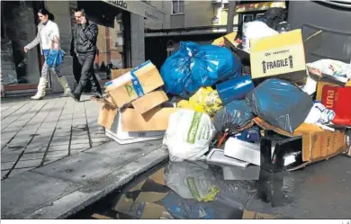  ?? L. R. ?? Dos personas caminan junto a la basura acumulada durante una huelga en Granada.