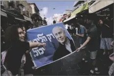  ?? AP PHOTO/MAHMOUD ILLEAN ?? People take photo with an election campaign poster depicting former Israeli Prime Minister and Likud party leader Benjamin Netanyahu at Mahane Yehuda market in Jerusalem a day ahead of Israeli national elections on Monday.