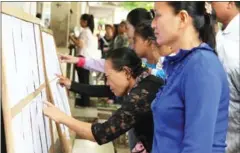  ?? HONG MENEA ?? People check voter lists at Phnom Penh’s Sothearos High school during national elections held in 2013.