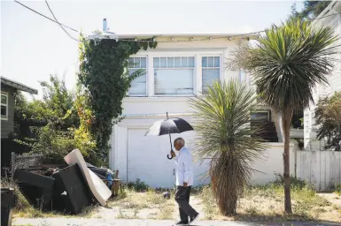  ?? Photos by Lea Suzuki / The Chronicle ?? Berhane Woldeabzgh­i takes cover from the sun as he strolls through his Oakland neighborho­od.
