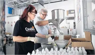  ?? AMY BETH BENNETT/SOUTH FLORIDA SUN SENTINEL PHOTOS ?? Co-owners Agnes and Bela Nahori fill bottles with hand sanitizer at Chainbridg­e Distillery in Oakland Park.