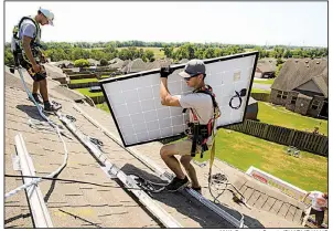  ?? NWA Democrat-Gazette/CHARLIE KAIJO ?? Installer Jarren Stinson carries a solar panel across the roof of a home Friday in Centerton in Northwest Arkansas. The embrace of solar power by a growing number of Arkansas homeowners has set off a debate over reimbursem­ents by utility companies.