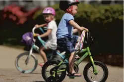  ?? STEPHEN M. KATZ/STAFF ?? Cole Pfeiffer, 3, with his sister Claire, 5, rides his bike in front of his Virginia Beach home on April 7. Parish Day School students are doing a virtual trike-a-thon for CHKD.