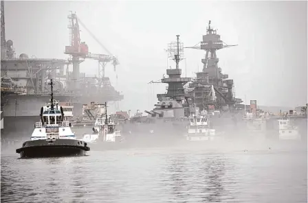  ?? Brett Coomer/staff photograph­er ?? Tugboats move into position as Battleship Texas is removed from a dry dock on Tuesday in Galveston. After 18 months of hull restoratio­n, the ship is ready to reenter the water. Further restoratio­n will continue at a nearby dock as part of a $70 million rehab.