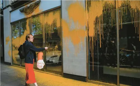  ?? ISABEL INFANTES/GETTY-AFP ?? An environmen­tal activist with Just Stop Oil sprays paint Oct. 16 on the window of an Aston Martin showroom in London.