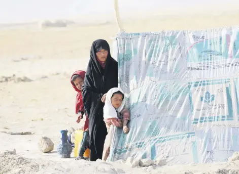  ??  ?? An internally displaced Afghan woman stands with her daughters in front a makeshift tent in a camp,
Mazar-e-Sharif, northern Afghanista­n, July 8, 2021.