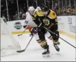  ?? JOHN MINCHILLO - THE ASSOCIATED PRESS ?? Boston Bruins center Sean Kuraly (52) skates the puck behind the New York Islanders net against defenseman Scott Mayfield (24) during the first period an NHL hockey game, Saturday, Feb. 29, 2020, in Uniondale, NY.