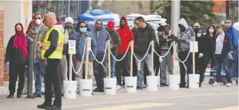  ?? GAVIN YOUNG ?? Shoppers wait in a physical-distancing lineup to get into to the Rona store in Sunridge on Sunday.