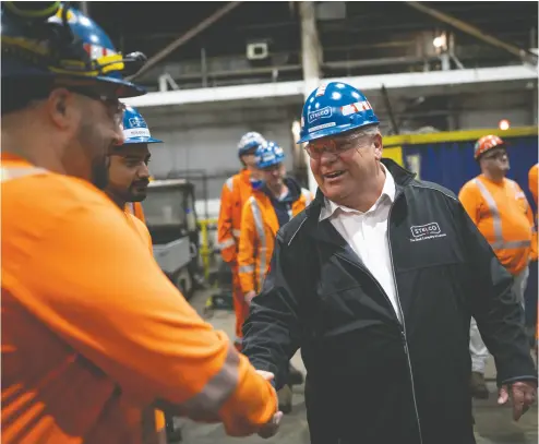  ?? PETER POWER / THE CANADIAN PRESS ?? Premier Doug Ford shakes hands with Stelco employees during an election campaign stop on Wednesday
at the steel mill in Hamilton. Ford is promising a $19.9-billion deficit this year, if re-elected in June.