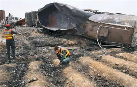  ?? Iram Asim/Associated Press ?? Pakistani rescue workers examine the site of an oil tanker explosion Sunday at a highway near Bahawalpur, Pakistan. The accident killed more than one hundred people who had rushed to the scene of the highway accident to gather leaking fuel, an official...