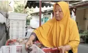  ?? ROBERTUS RISKY/JAWA POS ?? TELAT INFORMASI: Latifah, penjual kue di Kampung Kue Rungkut, menata jajanan yang masih banyak hingga kemarin siang.