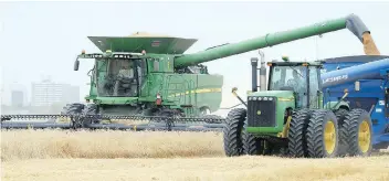  ?? TROY FLEECE ?? Rolo Farms employees Jonathan Harder and Adrian O’Quinn operate a combine and a grain cart. Healthy grain prices in recent years have buoyed the price of agricultur­al land.