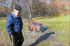  ?? CHARLES PRITCHARD - ONEIDA DAILY DISPATCH ?? A member of the Canastota American Legion walks by the pile of flags being retired on Nov. 112017.