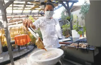  ?? Photos by Scott Strazzante / The Chronicle ?? Homekitche­n entreprene­ur Cheska Kistner grills in the backyard of her home in Benicia.