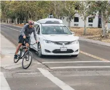  ?? JULIA WANG/WAYMO VIA THE ASSOCIATED PRESS ?? A Chrysler Pacifica minivan using Waymo’s self-driving car technology is tested with a company employee as a biker at Waymo’s facility in Atwater, Calif.