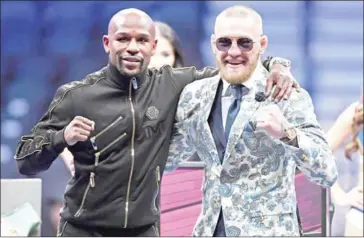  ?? ETHAN MILLER/GETTY IMAGES/AFP ?? Floyd Mayweather Jr (left) and Conor McGregor pose for pictures at a news conference after Mayweather’s 10th-round TKO victory in their boxing match on Saturday.