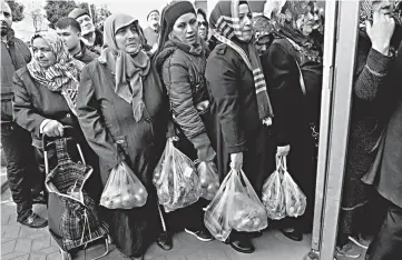  ??  ?? People wait in line to buy vegetables sold in a tent set up by the municipali­ty in the Bayrampasa district of Istanbul, Turkey. — Reuters photo