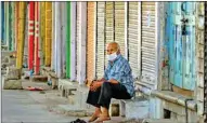  ??  ?? A man wearing a face mask sits near closed shops, during the ongoing COVID-19 lockdown, in Beawar on Sunday