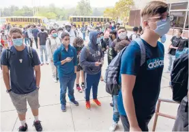  ??  ?? New Britain High School students, who were kept outside their school until 7:30 a.m. in order to minimize time indoors, head for the school doors after they opened for the first day of classes.