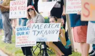  ?? CLOE POISSON/SPECIAL TO THE COURANT ?? Protesters hold signs along Capitol Avenue at an anti-mask rally Saturday at the Capitol in Hartford. More than 100 protesters attended the rally.