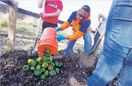  ?? PHOTOS BY LUIS SÁNCHEZ SATURNO/THE NEW MEXICAN ?? Waylon Lopez, 16, a New Mexico School for the Deaf student, empties a bucket full of bell peppers last week in the compost pile in the Railyard Park’s Community Garden.