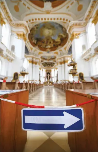  ?? FOTO: FELIX KÄSTLE/DPA ?? Schilder und Absperrban­d sollen in der Basilika in der Basilika in Ulm-Wiblingen dafür sorgen, dass die Gläubigen während der Messe genug Abstand halten.