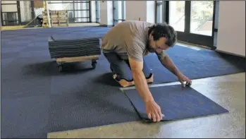  ?? The Sentinel-Record/Max Bryan ?? NEW SQUARES: JGP Inc. contractor Anthony Brown lays down carpet squares in the concourse outside the Hot Springs Convention Center Arena Thursday afternoon.