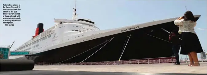  ??  ?? Visitors take photos of the Queen Elizabeth II luxury cruise liner, also known as the QE2, docked at Port Rashid in Dubai, where it will be moored permanentl­y as a newly refurbishe­d floating hotel.
— AFP photos