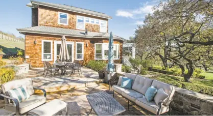  ??  ?? A stone patio with an outdoor fireplace stretches behind the Novato home.