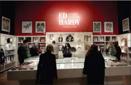  ?? JEFF CHIU — THE ASSOCIATED PRESS Photos and text from wire services ?? In this Wednesday photo, visitors look through merchandis­e for sale during a media preview of “Ed Hardy: Deeper than Skin” at the de Young Museum in San Francisco.