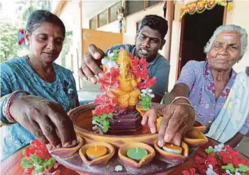  ?? PIC BY SYAMSI SUHAIMI ?? N. Jayanthi (left) and her mother-in-law, K. Popamal (right), decorating their home with the help the former’s nephew, R. Ram Kumar, in Kerilla Estate in Tanah Merah yesterday.