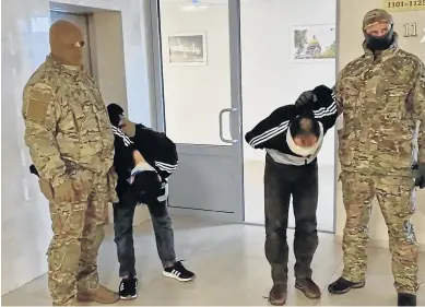  ?? REUTERS ?? Dos agentes de las fuerzas de seguridad rusas retienen ante las cámaras a dos de los once arrestados tras el atentado del viernes en una auditorio situado en las afueras de Moscú.