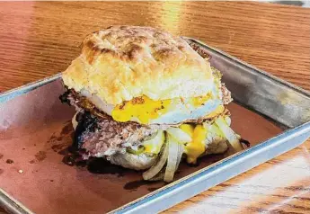  ?? Photos by J.C. Reid ?? The Brisket Biscuit features grilled onions and jalapeños, a fried egg, cheese, and bacon jam.