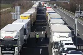  ?? RONALD ZAK — THE ASSOCIATED PRESS ?? Trucks stand on the highway close to the border between Austria and Hungary near Bruck an der Leitha, Austria, Wednesday. Hungary has closed the border due to the new virus outbreak.