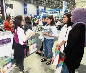  ??  ?? Disseminat­ing informatio­n: Sarnal (left) explaining the programmes at Cyberjaya University College of Medical Sciences to a group of schoolleav­ers at the fair.