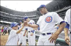  ?? PAUL BEATY / AP ?? Spencer Brown, 7, the grandson of Hall of Fame player Ron Santo, greets Carlos Marmol after throwing the ceremonial first pitch Friday at Wrigley Field.