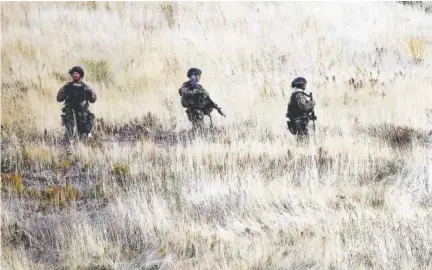  ?? Ravell Call, The Deseret News ?? Law enforcemen­t officials comb a hillside near Salt Lake City’s Red Butte Canyon on Tuesday in search of a suspect in a shooting. Austin Boutain surrendere­d later Tuesday at a library.