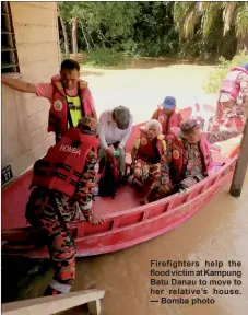  ?? ?? Firefighte­rs help the flood victim at Kampung Batu Danau to move to her relative’s house. — Bomba photo