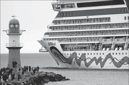  ?? BERND WUESTNECK / DPA VIA ASSOCIATED PRESS ?? Crew members stand on board and wave as the Aidasol leaves the Baltic Sea resort after a one-week stay at a cruise terminal in the city of Warnemuend­e, near Rostock, Germany, on May 1. The ship visited the city without passengers for safety concerns caused by the COVID-19 pandemic.